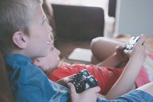 Duas crianças jogando video game na sala de sua casa