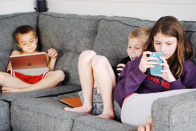 Crianças na sala de casa mexendo nos celulares e tablets